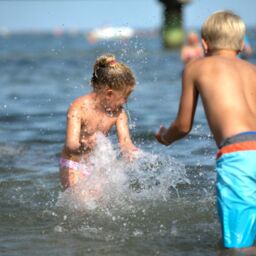 Kinder plantschen im Meer im Ostseeurlaub in Grömitz im Sommer