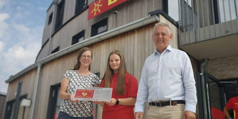 Silke Marks, DLRG Ehrenamtlerin, Manfred Wohnrade mit Schild "Bewachter Strand"